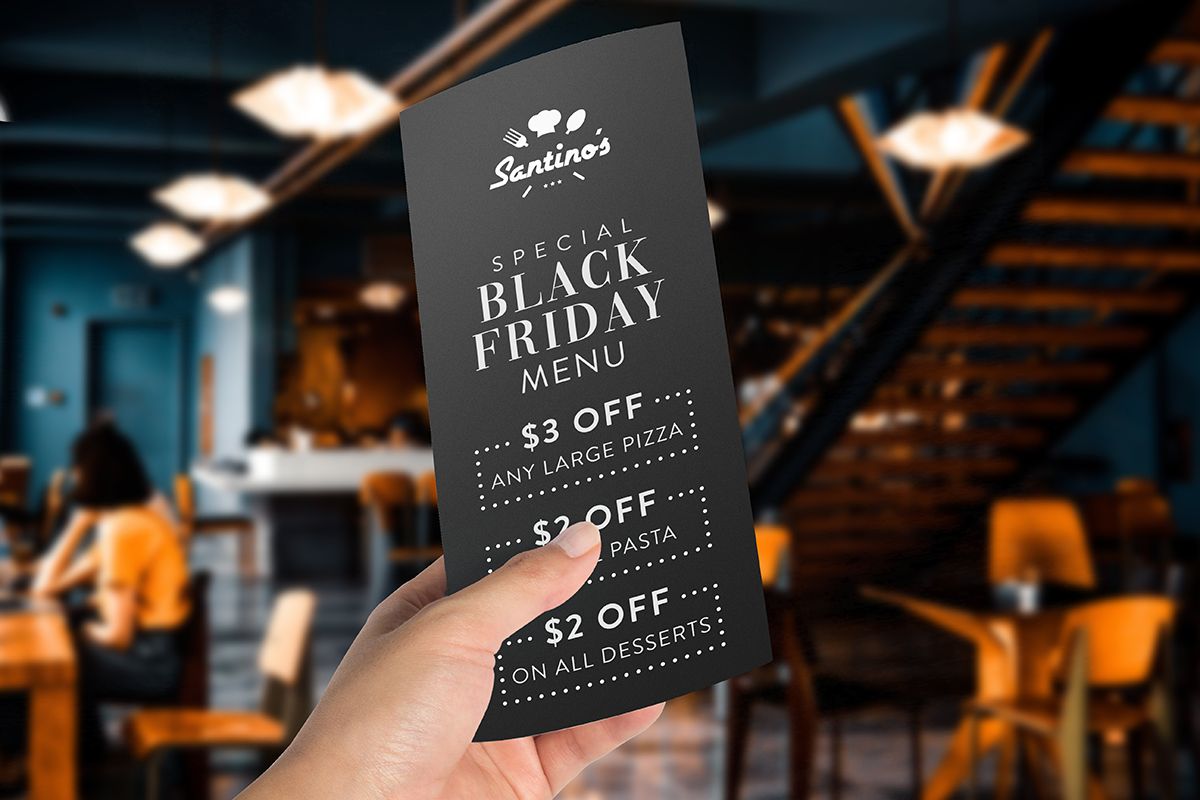 A Black Friday restaurant menu held in a hand inside a restaurant.