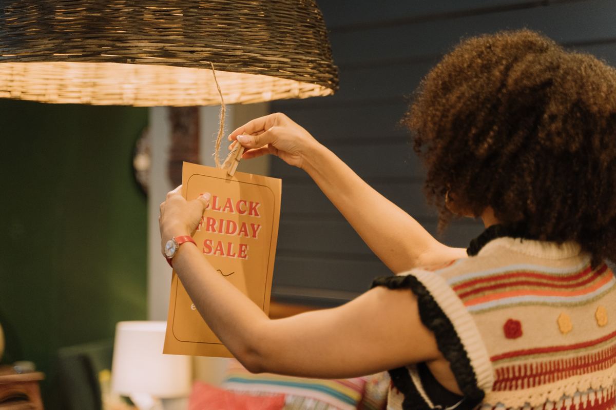 A woman hanging a postcard stating a black friday sale.