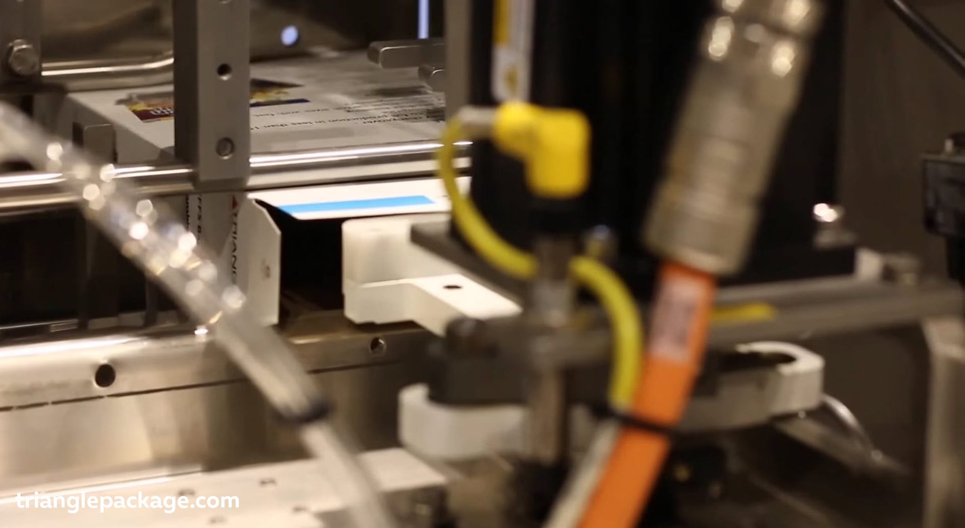 A stack of flat packaging boxes on a box erector system of an automated cartoning machine.