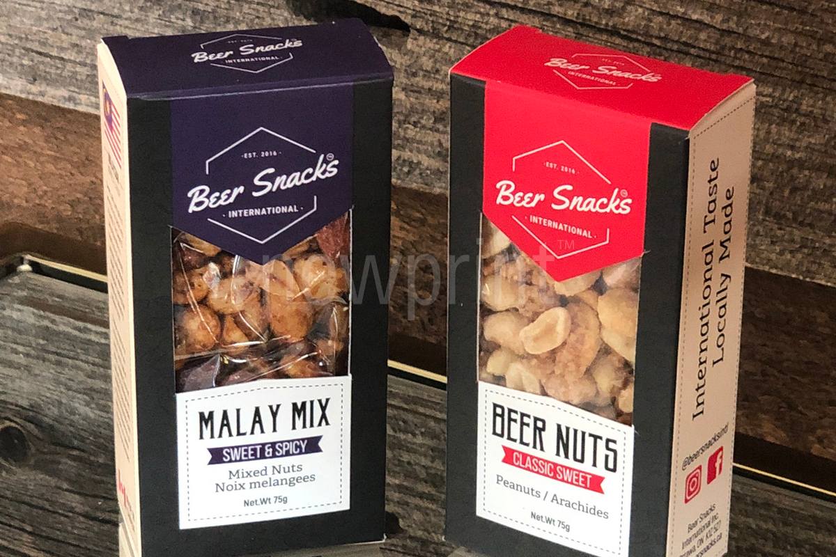 Two custom food packaging boxes containing nuts and snacks against a wooden background