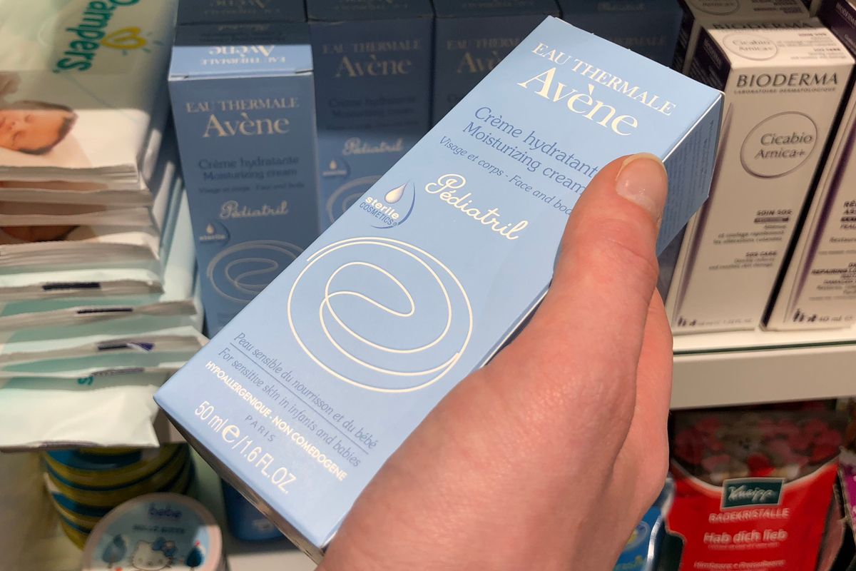 Moisturizing cream cosmetic packaging box held in a hand.