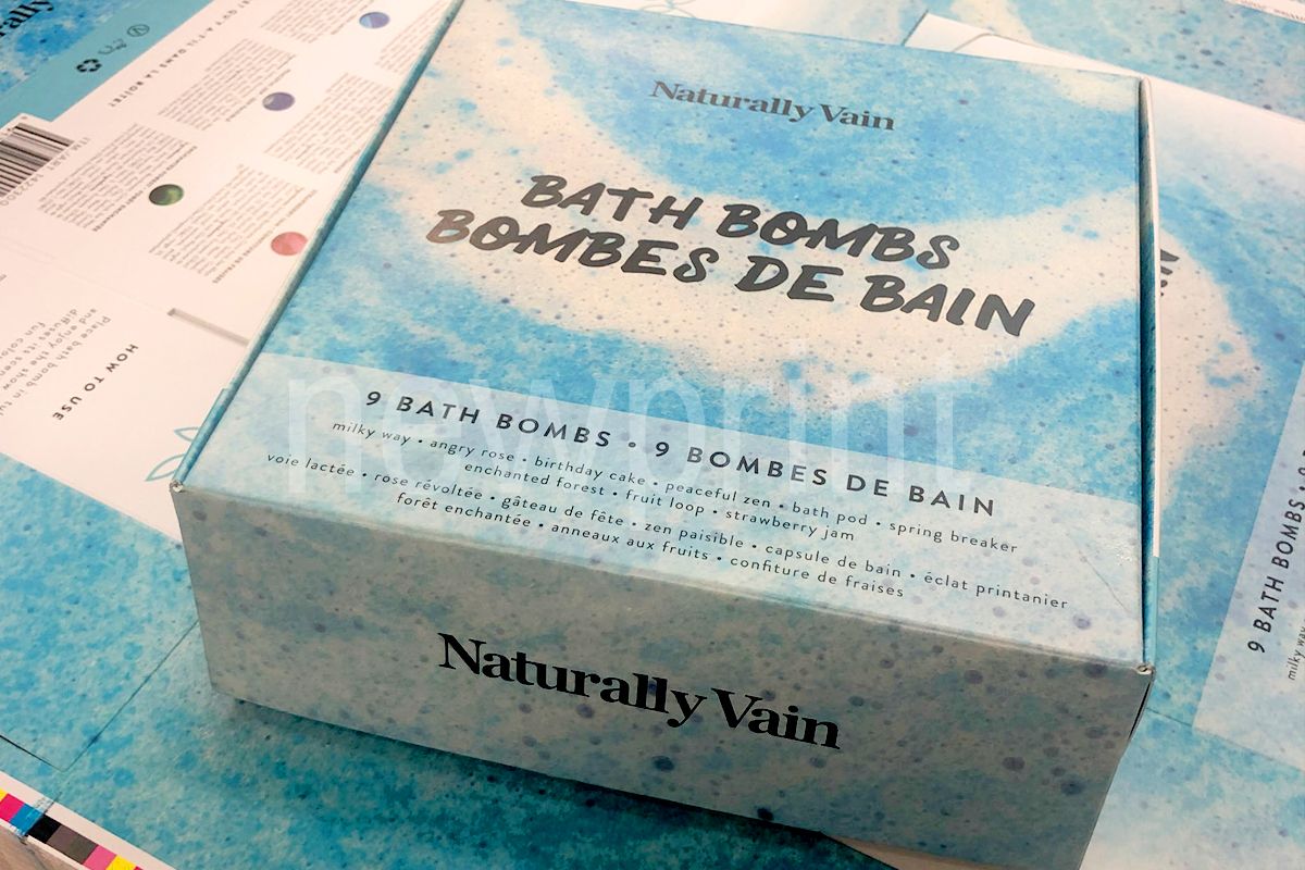 How to Choose the Right Packaging for Your Product - custom printed packaging box - An assembled roll end front tuck box for bath bombs packaging, sitting on a pile of uncut printed sheets