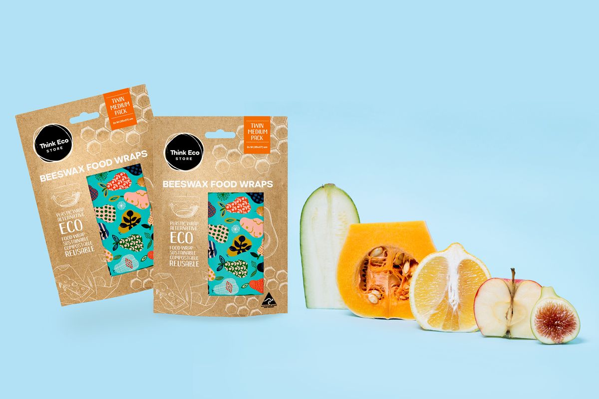 Two beeswax food wrapers packagings with sustainable packaging designed and five different fruits on the side 