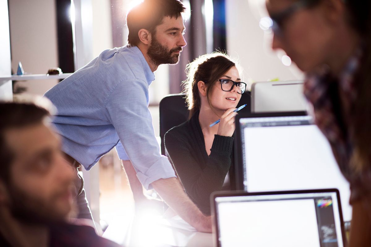 Web to print example - Four people in the office, two looking at the screen, and two talking