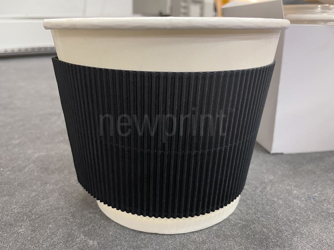 Paper sleeve wrapped around a paper cup that serves as a hard copy proof in the process of creating product packaging.