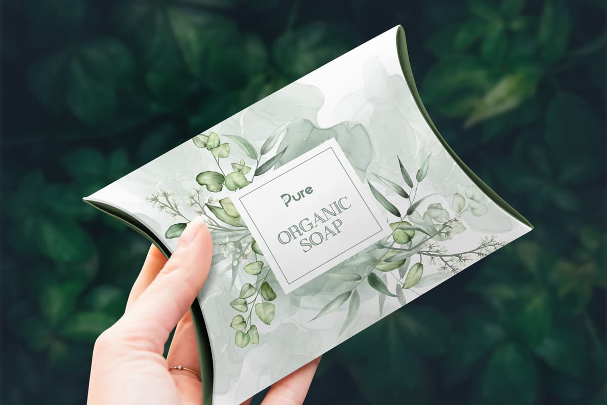Image showing a hand holding a Pillow Box made to be cosmetics packaging with nature design on it.
