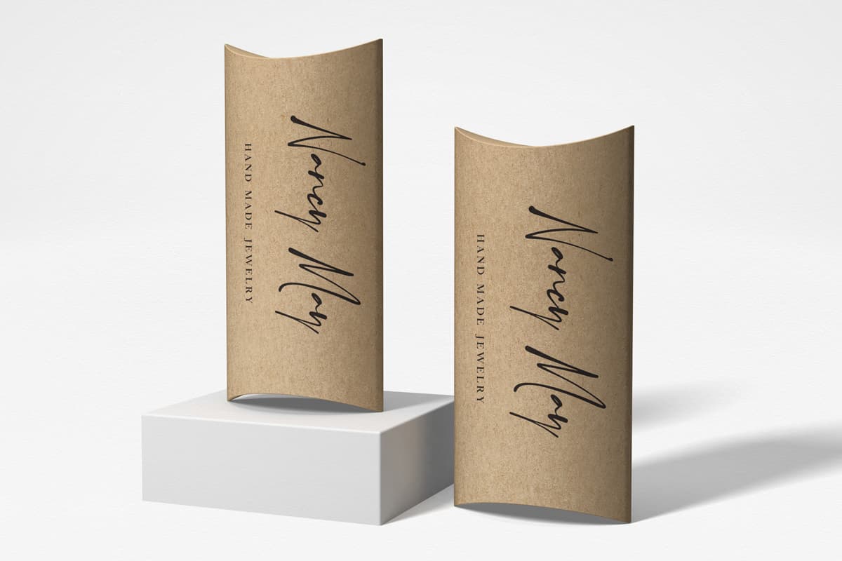 Image showing two kraft Pillow boxes made to be jewelry boxes with logo design on them, on white background.