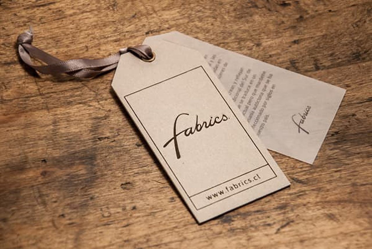 One of the hang tag examples on the wooden background, simple kraft paperboard, with stylized font.