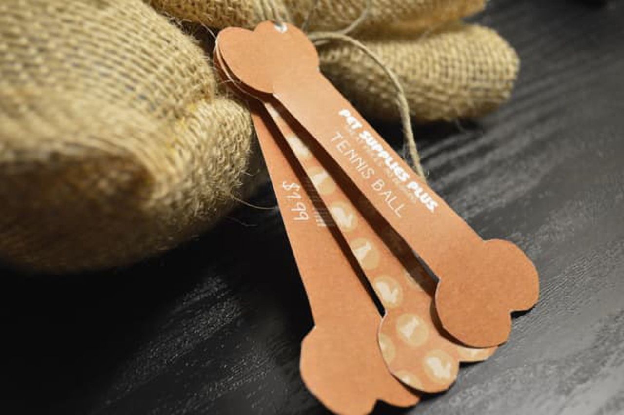 One of the three piece hang tag examples for pet supplies shaped like a bone.