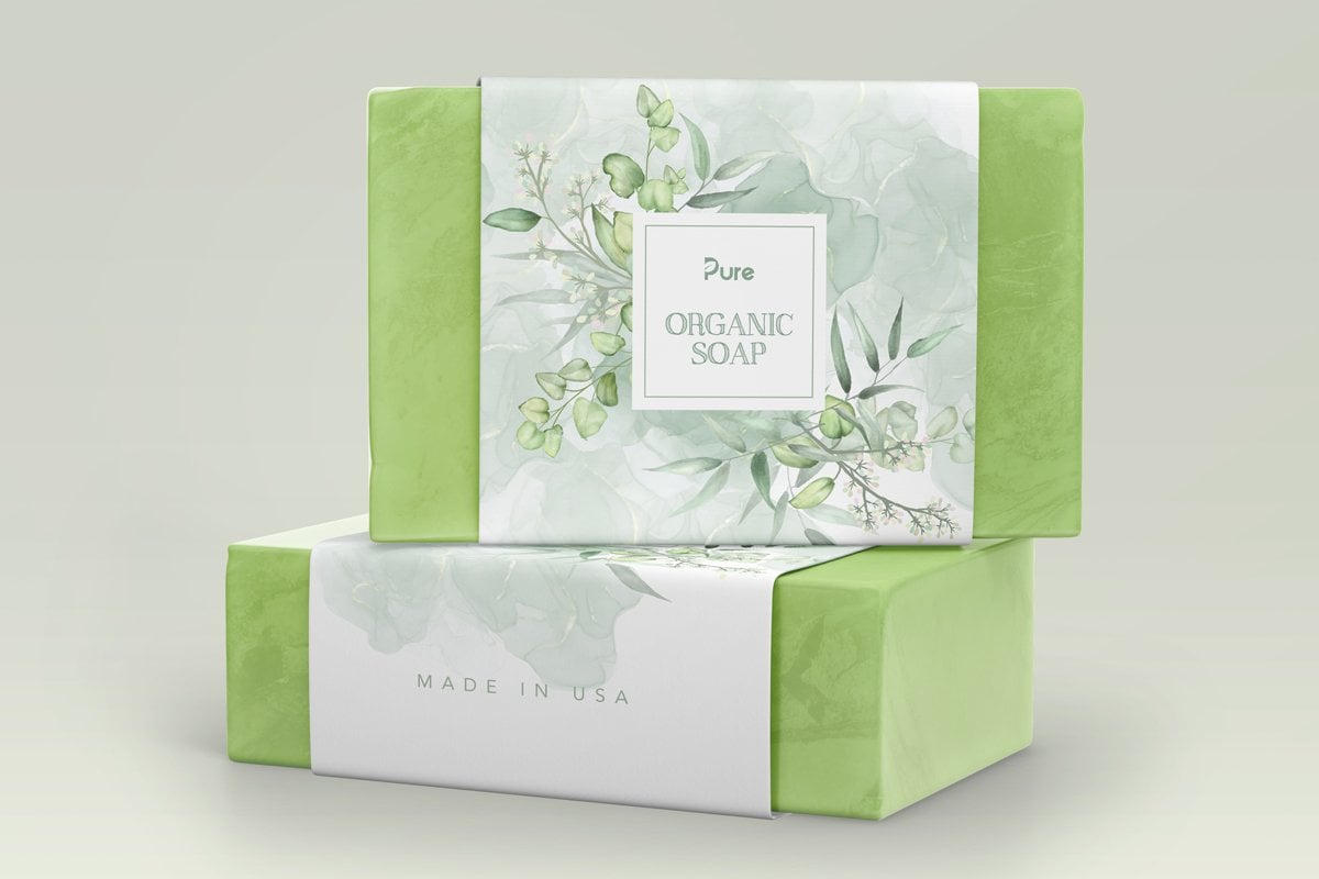 Two natural green soaps with packaging sleeves making made in USA claims on them.