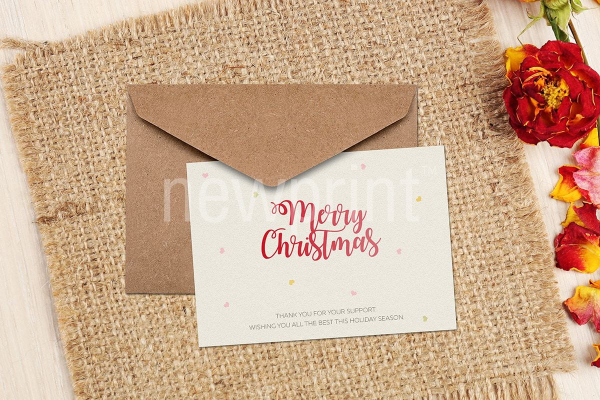 Greeting card saying Merry Christmas on it placed on the envelope with flowers on one side of the image as one of seasonal marketing ideas.