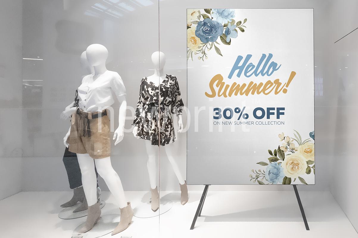 Seasonal marketing ideas - clothing store window display with three manikins and a banner advertising summer sale.