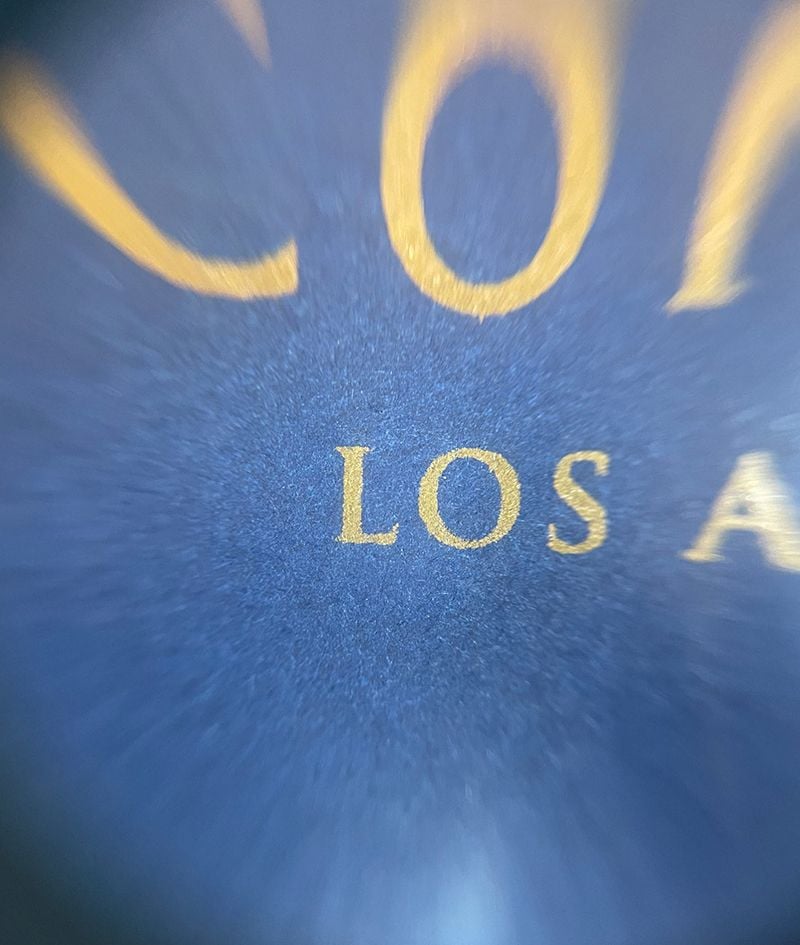 Spot color vs CMYK, a view through a magnifying glass showing the texture of paper on an envelope and the coverage of printed ink.