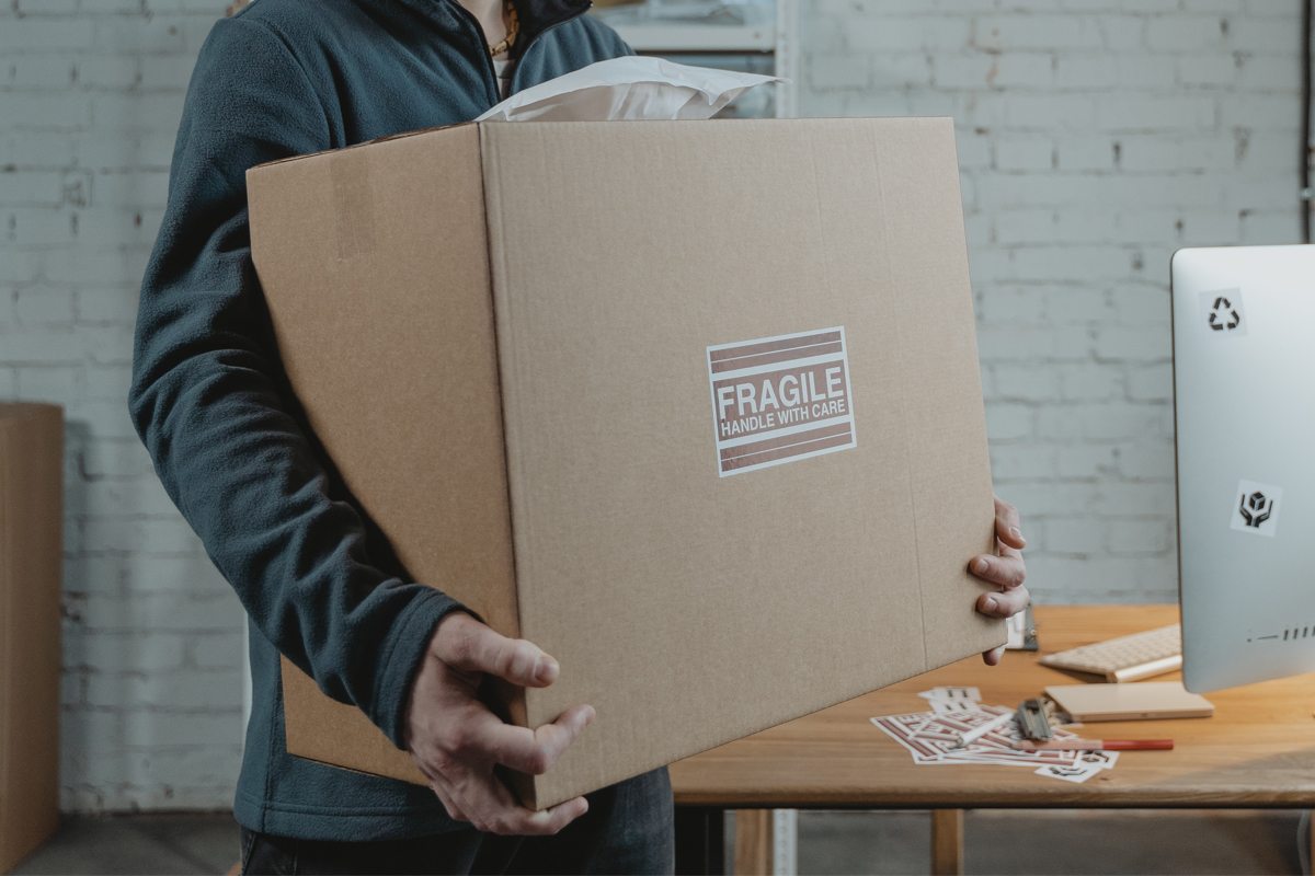 Types of packaging products - man holding a larg shipping box in his hands.