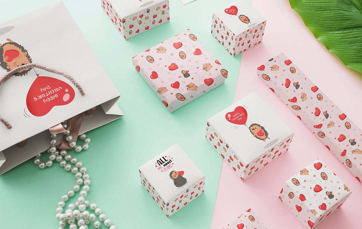 Valentine’s Day packaging, several small boxes, a paper bag, and wrapping paper with hedgehog and hearts  design.